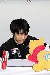 くまのプーさんのティッシュケースをつかむ羽生結弦の写真