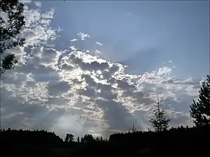 太陽を覆い隠し、隙間から光芒が差す不透明高積雲
