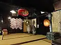 平野屋の「寄付（よりつき）の間」。金屏風、素焼きの大壺、花笠、竹製の丸提灯などで飾る。神棚も祀られている。