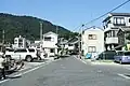 P.画像Oの画像から右折したところ。この先の道が狭い為一方通行になっている。画面左側公衆便所前に県が設置した架橋計画を宣伝する看板が設置されている。この先を直進すると画像Kの交差点に戻る。