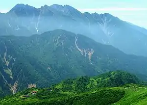 小池新道新道から見下ろす鏡平山荘、遠景は奥丸山と穂高岳(2004年8月12日)