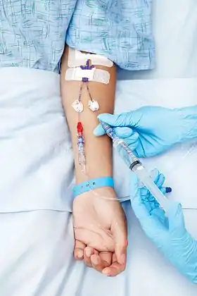 Photo of a person being administered fluid through an intravenous line or cannula(英語版) in the arm