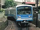 緑町駅に進入してくる電車。写真の奥が大雄山駅側で、上部の高架線が東海道線、撮影アングルの背後が緑町駅となる。この急カーブがあるため、大雄山線は20m車体の車両が入線できない。