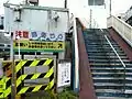 踏切保安係詰め所と、踏切隣に設置されている跨線人道橋入口。
