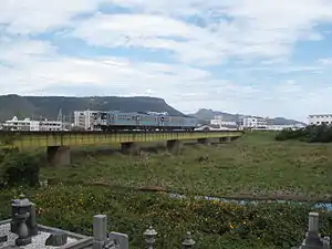 屋島を背にして春日川を渡る1000形気動車による高徳線の普通列車