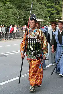 京都の時代祭において復元された中世の腹当を着用して通りを歩く男性