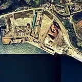 陣屋町臨港駅と崎守埠頭専用線
1976年撮影、周囲約1km範囲。臨港駅事務所は右端の青い小さな家屋。崎守埠頭の末端まで専用線が敷かれ、木材チップが積込まれている。写真右上には新線上に移設された崎守駅が見える。国土交通省 国土地理院 地図・空中写真閲覧サービスの空中写真を基に作成