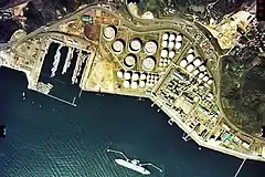 陣屋町貨物駅
1976年の陣屋町貨物駅と臨港線、周囲約1.5km×1km範囲。右が東室蘭方面。写真右上近くのカーブの中央部、海側の灰白色の建物が当駅事務所で、本線はここから東側は新線の造成中であり、まだ海側を通る旧線ラインを使用している。現在ではほぼ直線のトンネル間となり、これにより当駅事務所は少し北側に移動した。また、臨港線の分岐位置も変更されている。
臨港線は左端の臨港駅構内でスイッチバックして、今では埋め立てられてJX製油所の一部となったかつての水面貯木場へ向けて伸びている。国土交通省 国土地理院 地図・空中写真閲覧サービスの空中写真を基に作成