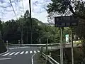 県道521号との交点（相模原市緑区佐野川字下岩、沢井入口バス停付近）。県道521号の重複区間から右折して棡原方面へ向かう。
