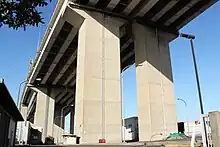 画像左:金城高架橋（工事中の名称は名港西大橋高架橋）。道路規格アップのため両側に拡幅された。画像右:金城高架橋の橋脚は短形断面として四隅を面取りした。橋脚中央にはスリットを設け、その中に排水管を設置した。