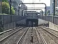 柴崎4号踏切構内より撮影した国領駅。写真中央、右側の上り列車のライトが映っている辺りにホームがある（2019年9月）