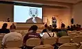 QtCon 2016 BerlinでKDEビジュアルデザイングループのリーダーであるJens ReuterbergがKonqiのemoticonをSteve Jobsの写真に載せてプレゼンをした。