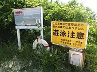 海岸入口の看板とAED。右側の看板は、赤色の「遊泳禁止」と黄色の「遊泳注意」(遊泳可能時)に差し替えられる。