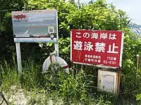 海岸入口の看板とAED。右側の看板は、赤色の「遊泳禁止」と黄色の「遊泳注意」(遊泳可能時)に差し替えられる。