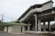 地上より見た久崎駅。左にある緑色の屋根の建物がトイレであり、右手の階段がある高架の下に駅への出入り口がある（2008年12月）