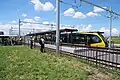 「ライトラインフラッグ授与式」が行われた平石停留場と開業記念特別列車（2023年8月26日）
