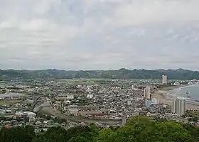 現代の鴨川地区(2014年撮影)魚見塚展望台から北方向の眺望。左手奥から右手前に加茂川が流れる。写真が中央に捉えているのが横渚で、右手前に橋(加茂川橋)が架かっているのが見える県道247号付近より海側が前原。加茂川右岸(写真左手から手前)がおおむね貝渚である。