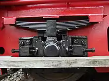 鉄道車両の懸架装置として使われる重ね板ばねの例。端部は車体の受に直接当てる方式で、中央部は胴締めで固定されている。