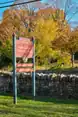 A rock wall and trees behind a large signpost