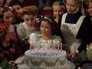 ハリウッド女優シャーリー・テンプルの子役時代の写真。1939年製アメリカ映画『テンプルちゃんの小公女』の一場面(テンプルの演じる少女サラが誕生日を皆に囲まれて楽しんでいる場面)で、撮影時は10~11歳であった。