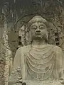 盧舎那仏坐像　河南省洛陽市、龍門石窟奉先寺洞　唐、上元年間（675年）　立体感や人体観察に基づいた写実性が見られる。玄奘や王玄策らによるインド文化流入も様式の確立へ影響を及ぼしたと考えられている。