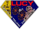 A diamond-shaped crest houses artworks of the Lucy fossil at left, the Lucy spacecraft at center, and an artist's impression of a Jupiter trojan. The word "Lucy" is written in a large, bold red font at the top right corner, while the words "First to the Trojans" and "SWRI&nbsp;· NASA&nbsp;· LM" are written in a smaller white font across the bottom edges of the diamond-shaped crest.