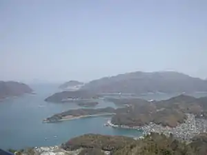(左)舞鶴市中心部周辺の空中写真。1975年撮影。中心部は大きく東西2地区に分かれている。画像左下方が西舞鶴地区。画像右上方が東舞鶴地区。国土交通省 国土地理院 地図・空中写真閲覧サービスの空中写真を基に作成。(右)舞鶴湾のリアス式海岸。