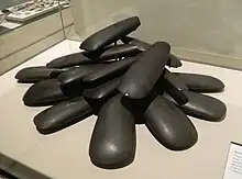  黒っぽい石の表面を滑らかに磨いて作った斧。19点ある