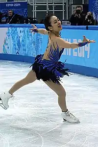 2014年ソチオリンピックのフリー演技中の浅田真央。3回転ループを着氷し右手を前に突き出している。