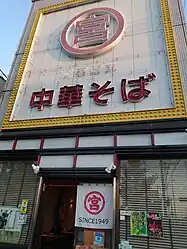 元車庫前 丸宮中華そば 本店（和歌山市毛見）。紀三井寺競技場前の派手な電飾が目印で、「元車庫前」としてブランディングを行っている