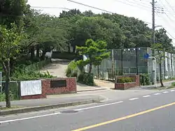 松戸市立河原塚中学校の正門及び、併設のテニスコートを撮影。正門を入ると、急な坂があり20mほど登り切ると、写真奥に見える校舎に到着する。