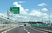 外回り本線流出部インター出口は春日井市だが画像奥の丘陵地帯は名古屋市守山区