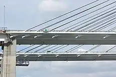 画像左:横から見たケーブル連結部。その間隔は端部になるほど密になる。画像右:一期線は車両衝突におけるケーブル保護のため防護ステイが斜めに設置された。