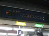 対面ホーム上方にあるLED式発車標。その下に点灯しているのが乗車位置目標の看板。