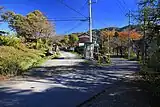 右側の舗装路が開通時の旧線跡、左側の砂利道が荒川橋梁架設後に新設された短絡線の跡。