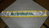 ミス・インターナショナル世界大会グランプリ用たすき(実際のたすきには「MISS」の前に受賞年度(西暦下二桁)が入る)