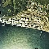 日本石油(後のJX)向け専用線
1976年撮影約1km範囲。室蘭本線が一旦山側の街寄りを走るが、ここより西の陣屋町まではまだ新線の造成中で、再び海縁を通る旧線ラインが使用されている。道路を隔てた海側には本輪西駅から本線に並行して来た専用線が留置線群と積込線に分かれ、左端の工場正門手前まで折り返し線が敷かれている。国土交通省 国土地理院 地図・空中写真閲覧サービスの空中写真を基に作成