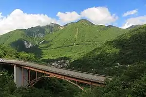 平湯峠方面の国道158号から望むアカンダナ山と山麓の平湯温泉街（2016年6月14日撮影）