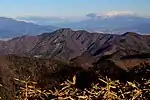 天子山地の竜ヶ岳から望む蛾ヶ岳、右奥に山頂部に雲がかかった八ヶ岳(2015年12月5日)