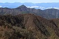 東側の本社ヶ丸方面から望む釈迦ヶ岳、左から日向坂峠を越えて東斜面に林道蕪入沢上芦川線が通る遠景は赤石山脈