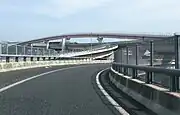 左へ急カーブするランプは名二環→伊勢湾岸道豊田方面への連絡路で、そのまま本線に合流。その上を名古屋南出口へのオフランプが跨ぐ（この構造から名二環→名古屋南出口へは連絡しない）