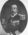 名和又八郎。伝承では水兵に椅子を投げつけ、岡本を救おうとした当直分隊監事である（明治29年12月の海兵職員名簿に海兵運用術教官として名和の名がある。）