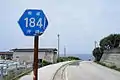県道184号線の標識と県道。港地区付近にて。（2012年）