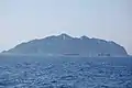 鳥居役の岩礁越しに（南東から）眺めた沖ノ島