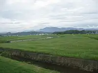 幸袋地域(現在は飯塚市の一部)の遠賀川。「この川のゆるやかな土堤は草に蔽われ、牛などが放牧してあって大そう牧歌的で、川すじなどという気分は感じられなかった。早春には、Hの妻と妹とがこの川の横で芹を摘み、つくしを採った」(「暗い活字」)。