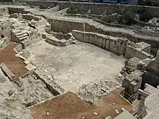 下部の形が不規則で大型の漆喰のプールがある、古代の建造物が発掘された地層を見下ろす。