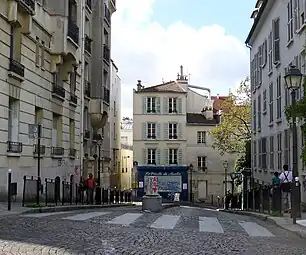 ジラルドン通り (Rue Girardon) は、南からオルシャン通りが交差するルピック通りムーラン・ド・ラ・ギャレット界隈から北側ダリダ広場方向へ走る。先に見える枝木はムーラン・ド・ラ・ギャレットの敷地。