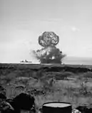 ブラボー実験。煙または粉塵が艦の前部マストを覆い、衝撃波が艦を超えて水上に広がっている。