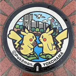 横浜市役所前に設置されたピカチュウのマンホール（ポケふた）。画像左がメス、右がオス。上空にはキャモメが飛んでいる（マンホール上部）。