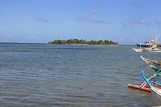  海上の島、600mほど、いくばくかのヤシが生えている。右に4艘の小船（bangkas）が移っている。